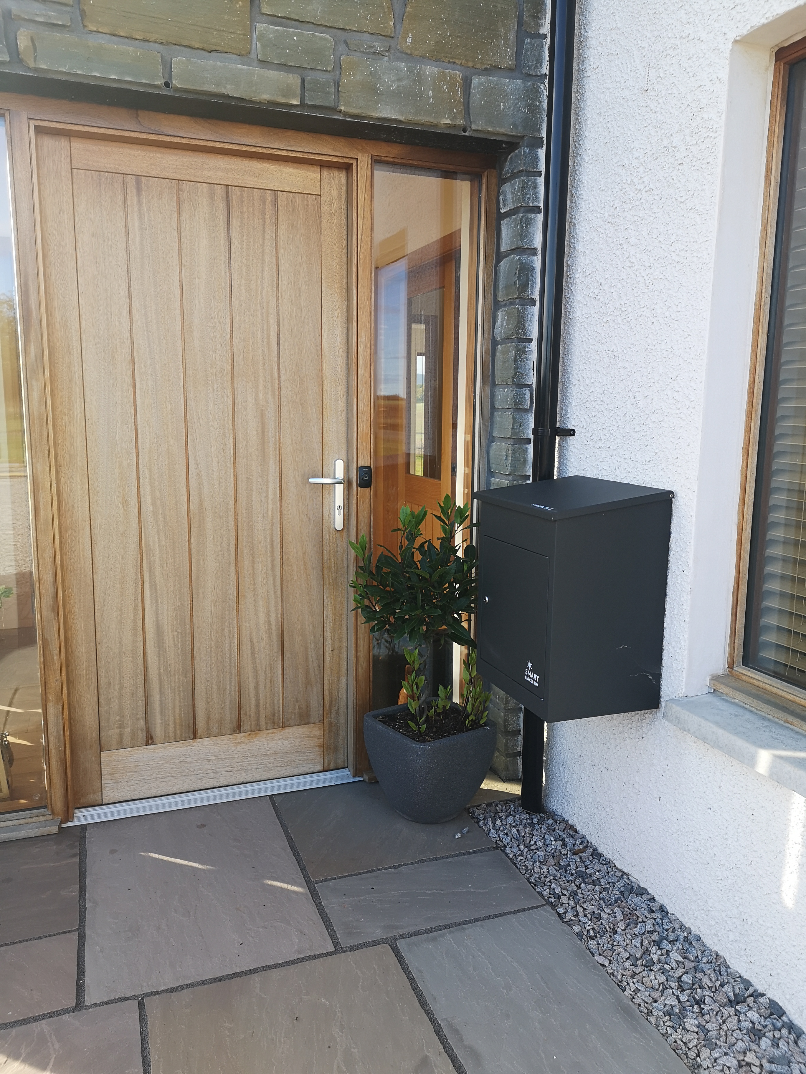 Grey black parcel collection box outside wooden door